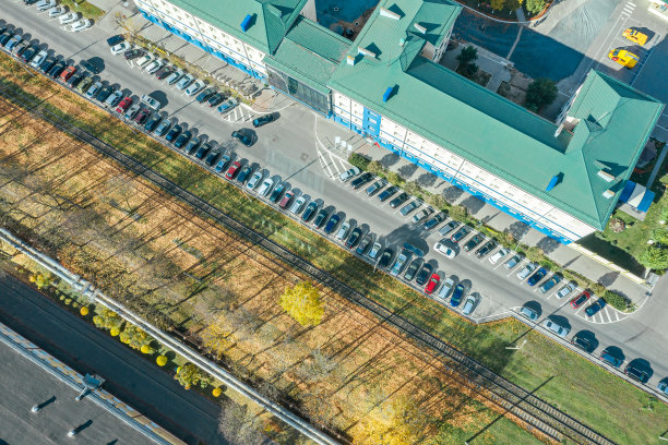 办公楼和停车场，有停放的汽车。阳光明媚的城市风景。图片下载