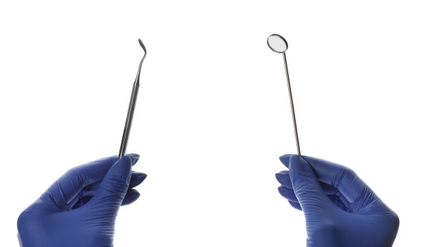 在白色背景上，牙医拿着口镜和塞子，特写图片下载