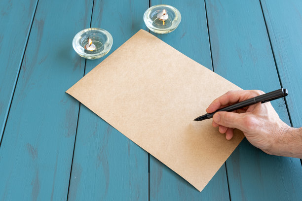 男人手里拿着自来水笔在一张牛皮纸上，准备签字。图片下载