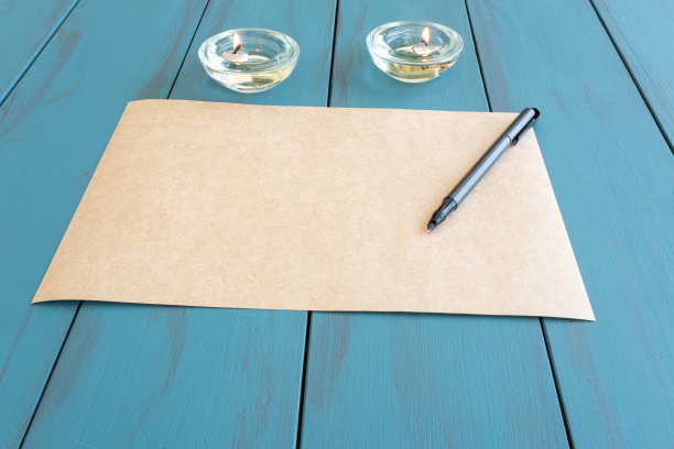 棕色纸上的钢笔，旁边是点燃的蜡烛——侧视图。图片下载