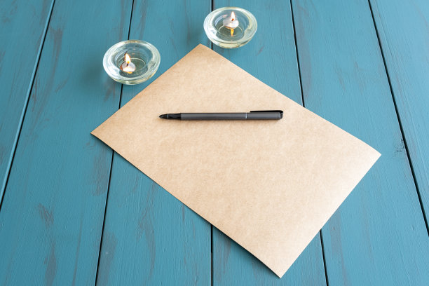 棕色纸上的灰色钢笔，旁边是点燃的蜡烛。图片下载