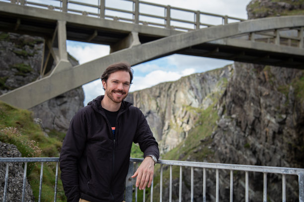 爱尔兰米森海德大桥上，一名白人男子倚在栏杆上微笑。悬崖上的背景图片下载