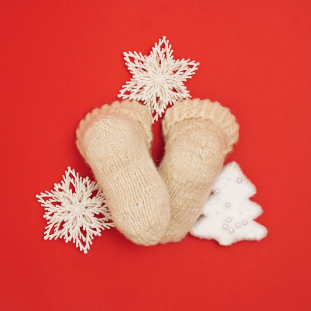 创意布局与婴儿羊毛袜子，圣诞和新年的装饰在充满活力的红色背景。寒假的概念。图片下载