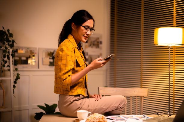年轻漂亮的女人在黄色衬衫工作很晚从家里的客厅深夜加班。女商人在工作场所低头看电脑。图片下载
