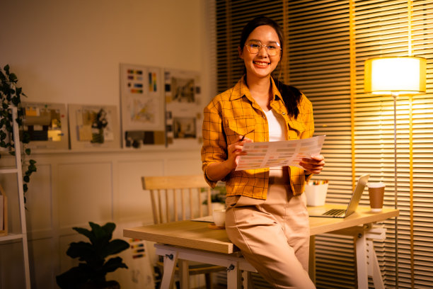 年轻漂亮的女人在黄色衬衫工作很晚从家里的客厅深夜加班。女商人在工作场所低头看电脑。图片下载