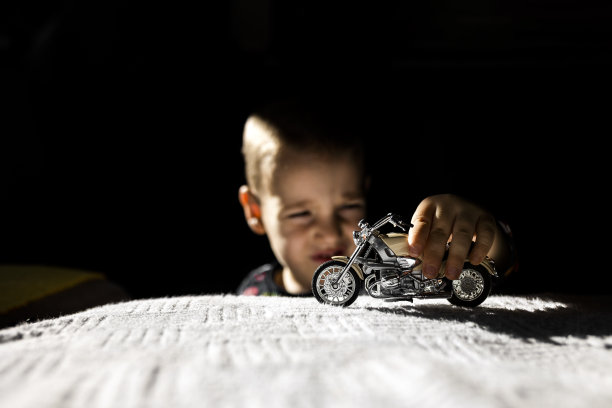 男孩在客厅玩玩具摩托车图片下载