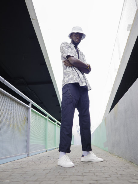 年轻的非裔美国男孩的肖像双臂交叉在室外走廊与栏杆两侧。带有复制空间的垂直照片。图片下载