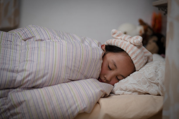 女孩戴着睡帽在床上睡觉图片下载