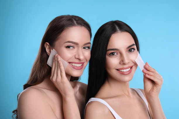 美丽的女人在浅蓝色背景上使用润色湿巾图片下载
