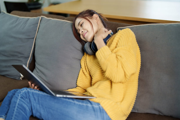 一个年轻的亚洲妇女在沙发上使用电脑的画像图片下载