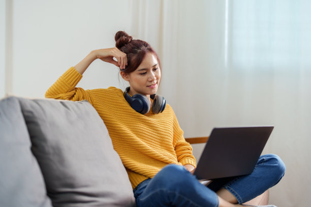 一个年轻的亚洲妇女在沙发上使用电脑的画像图片下载