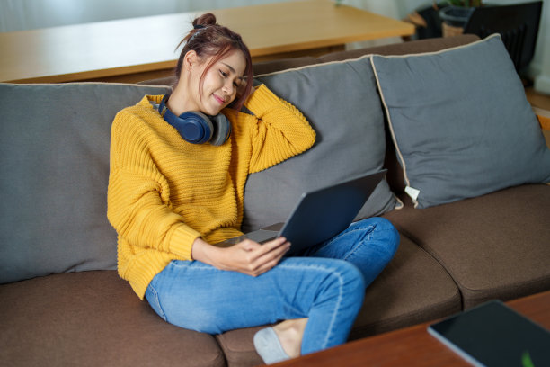 一个年轻的亚洲妇女在沙发上使用电脑的画像图片下载