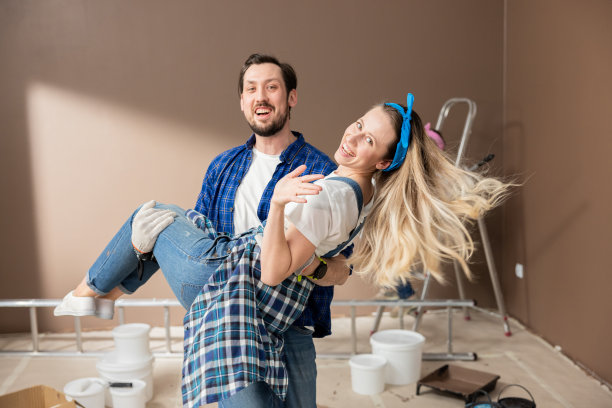 男人抱着女人装修公寓的喜悦，粉刷婴儿房，幸福的家庭搬进新家图片下载