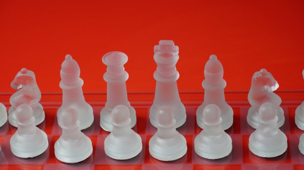 透明的国际象棋棋子，在反射棋盘上的起始位置，红色调。战略国际象棋棋盘游戏图片下载