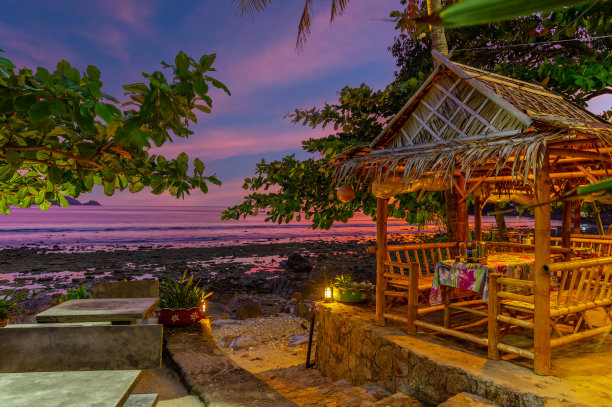 在泰国普吉岛的Kalim海滩上的日落。可爱的蓝绿色海水，郁郁葱葱的青山，五彩缤纷的天空图片下载