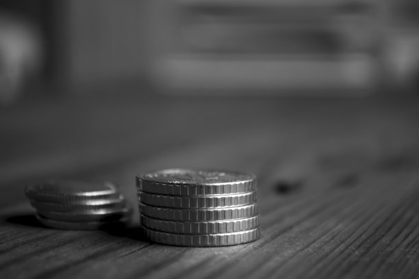 木桌上有两叠硬币。币方微距射击。钱在桌子上。铁鳗堆在一起。图片下载