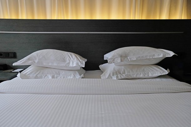 卧室:房屋或旅馆现代室内的卧室的一部分深色的床，柔软的枕头和羽绒被，时尚舒适的家具。图片下载