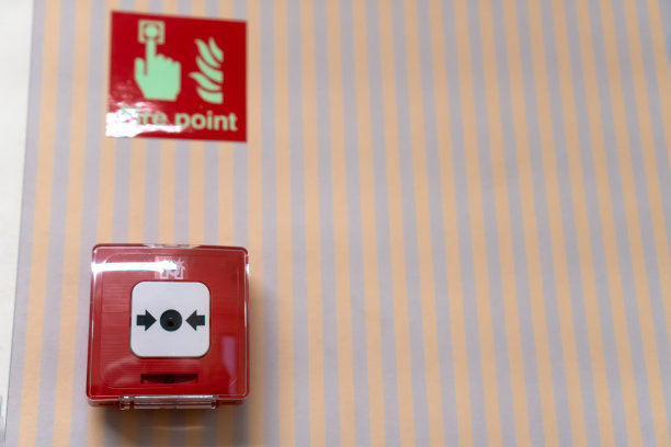 条纹墙上的红色火灾警报按钮的特写。有选择性的重点图片下载