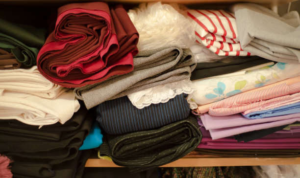 织物背景。架子上各种各样的纱线和织物。条纹和平原。红色和蓝色。缝纫厂。选择。缝纫和销售。图片下载