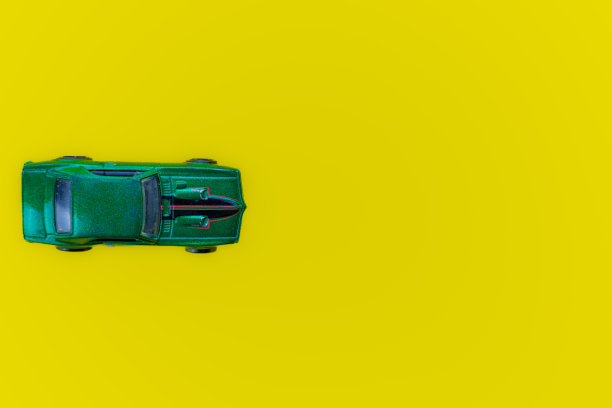黄色背景上的绿色玩具车。俯视图图片下载