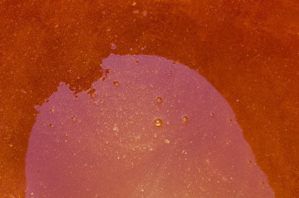 纹理。表面有一层浓稠的红橙色液体蜂蜜。容器的顶部阴影。图片下载