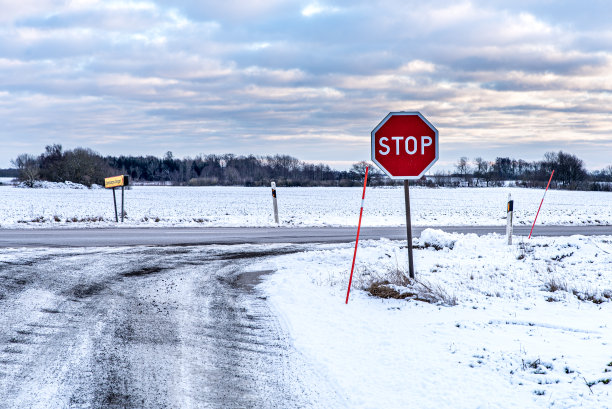 瑞典乡村结冰的道路上有一个停止标志。被雪覆盖的北欧道路。云和冰给人一种荒凉的感觉。忧郁的概念——瑞典斯坎县图片下载