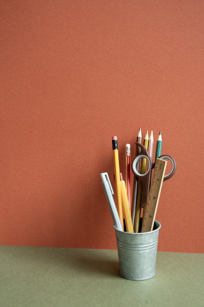 卡其色书桌上的铅笔架。红色的背景墙。工作区,办公用品图片下载