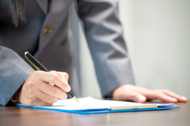 职场特写人物职业女商人坐在桌子前拿着笔签署或签署合同文件。女员工在办公室用书面形式写公司协议文件图片下载