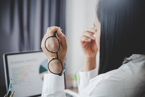 年轻的商业女性人昏昏欲睡，有沮丧的眼睛问题和头痛病，因为使用笔记本电脑在她的办公桌上。压力大的女员工因过度工作而疲惫不堪。图片下载