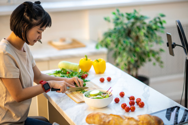 主妇在智能手机摄像头前准备蔬菜沙拉图片下载