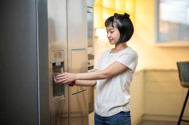 年轻女子使用冰箱饮水机图片下载