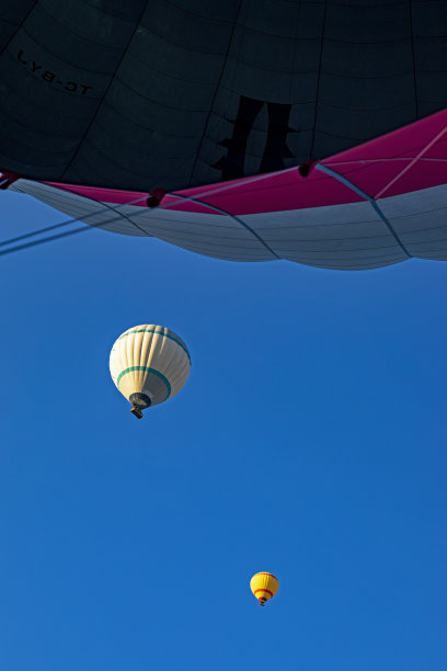 飞行的热气球在早晨从下面俯瞰蓝天，垂直图片下载