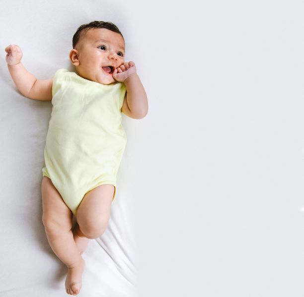 身穿黄色紧身衣的男婴躺在白色背景上图片下载