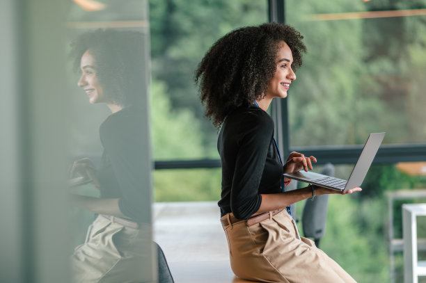 黑发可爱的年轻女士，办公室里有一台笔记本电脑图片下载