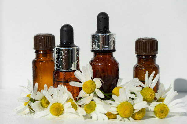 小玻璃瓶罗马洋甘菊精油在旧的木制背景。图片下载