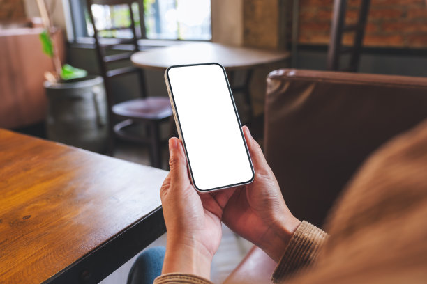 在咖啡馆里，一个女人拿着空白桌面屏幕的手机的模型图像图片下载