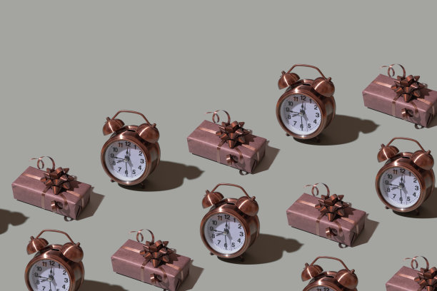 棕色礼盒模板与弓和闹钟在灰色背景。节日简约的概念图片下载