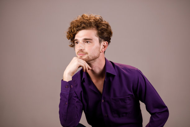 姜黄色卷发，穿着紫色衬衫，手托着下巴图片下载