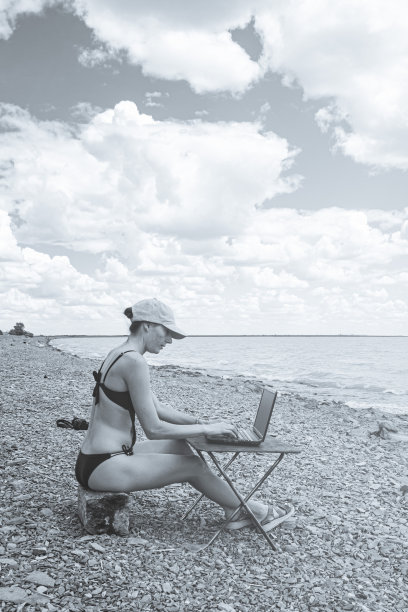 性感的自由职业女孩穿着性感的泳衣在海边的电脑前工作，自由的工作不受居住地的限制图片下载