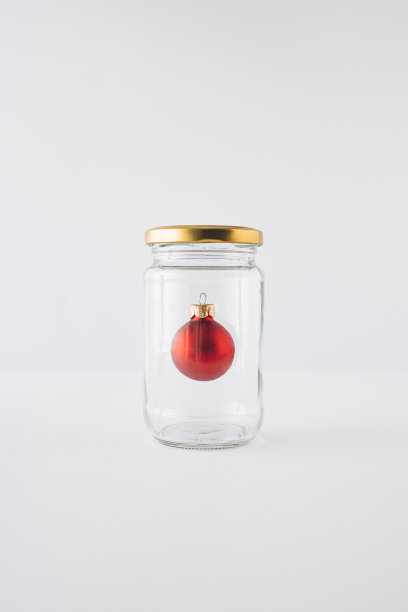 白色背景的玻璃罐里的红色圣诞小玩意。最小的概念。图片下载