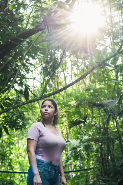美丽的拉丁女孩在哥伦比亚丛林中探索，徒步在被绿色自然包围的森林深处。阳光从树枝间照射进来。用于复制文本的空间图片下载