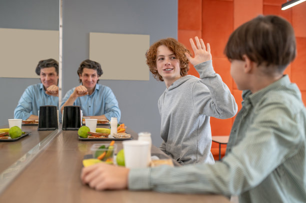 在食堂里观察一个学生和朋友打招呼的学校老师图片下载