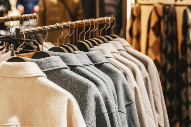 优雅的日常休闲外套挂在服装店的衣架上，模糊了店内的气氛图片下载
