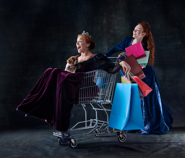 肖像的两个美丽的女人在女王的形象孤立在黑暗的背景。欢快的皇家购物图片下载