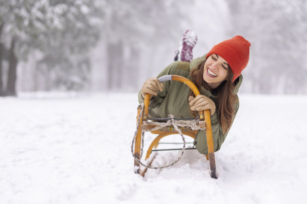 寒假里，躺在雪橇上的女人在雪地里从山上滑下来，玩得很开心图片下载