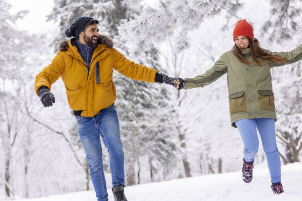 一对情侣在寒假的雪地里奔跑图片下载