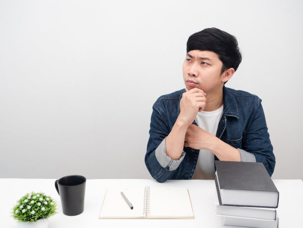 男人坐在书桌前拿着书看着抄写空间手势思考图片下载