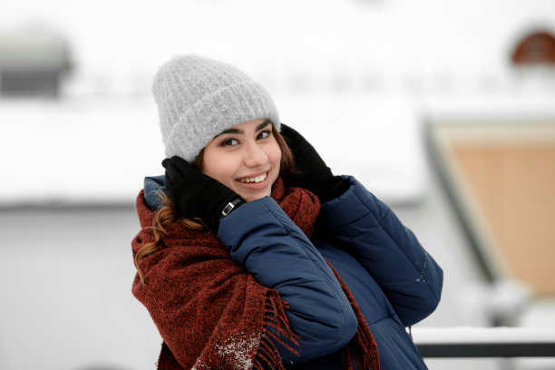 画像一个年轻快乐的女人享受冬天戴着围巾和帽子。图片下载