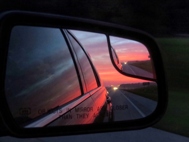 晚霞在后视镜的汽车反射的汽车侧在道路上图片下载