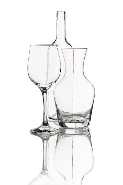 静物与空的透明酒瓶，醒酒器和酒杯。工作室拍摄与自然反射隔离在白色背景上。图片下载
